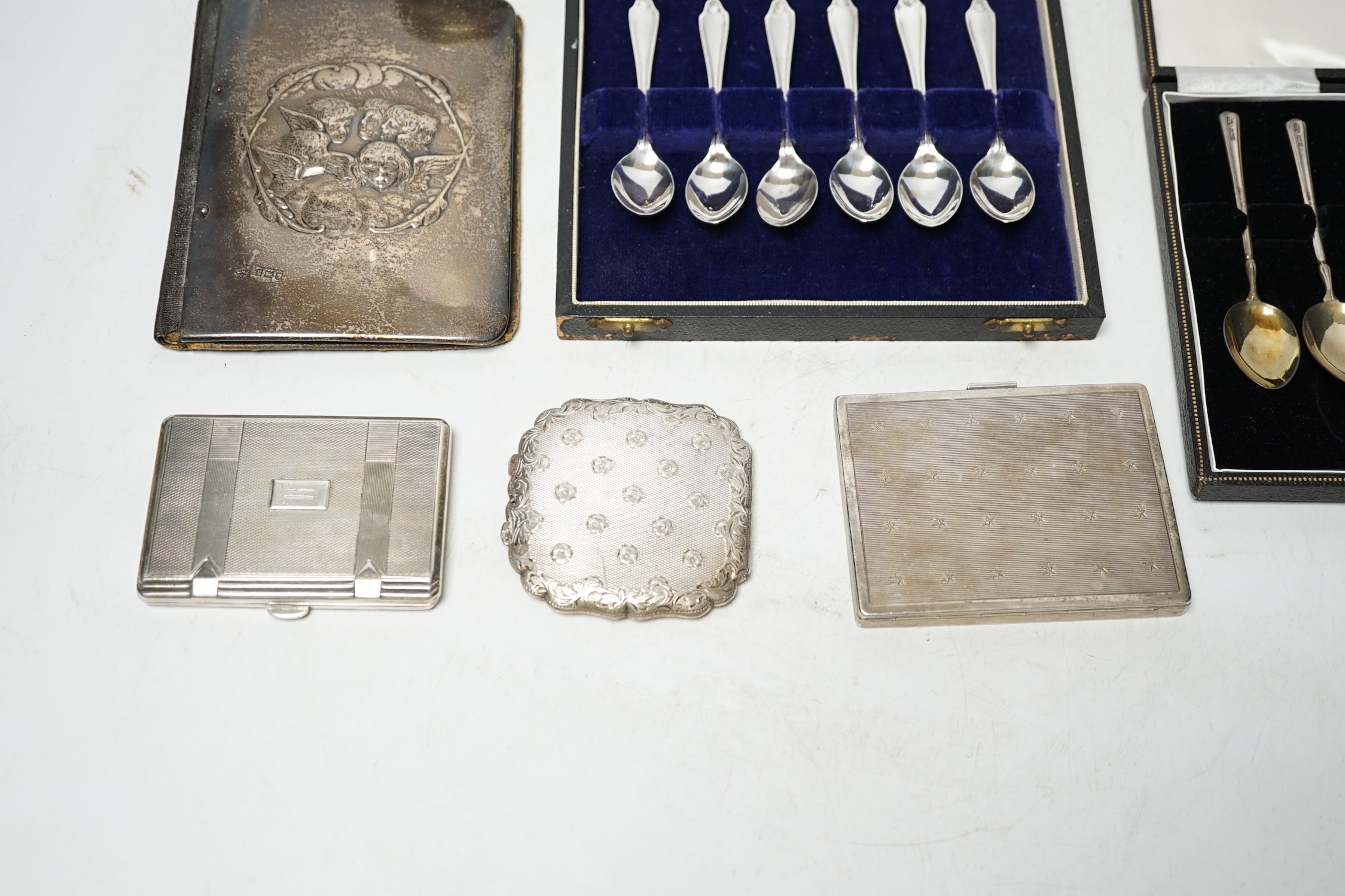 Two cased sets of six silver coffee spoons, a silver mounted leather case, two white metal cigarette cases, a white metal compact and a toilet jar. Condition - poor to fair